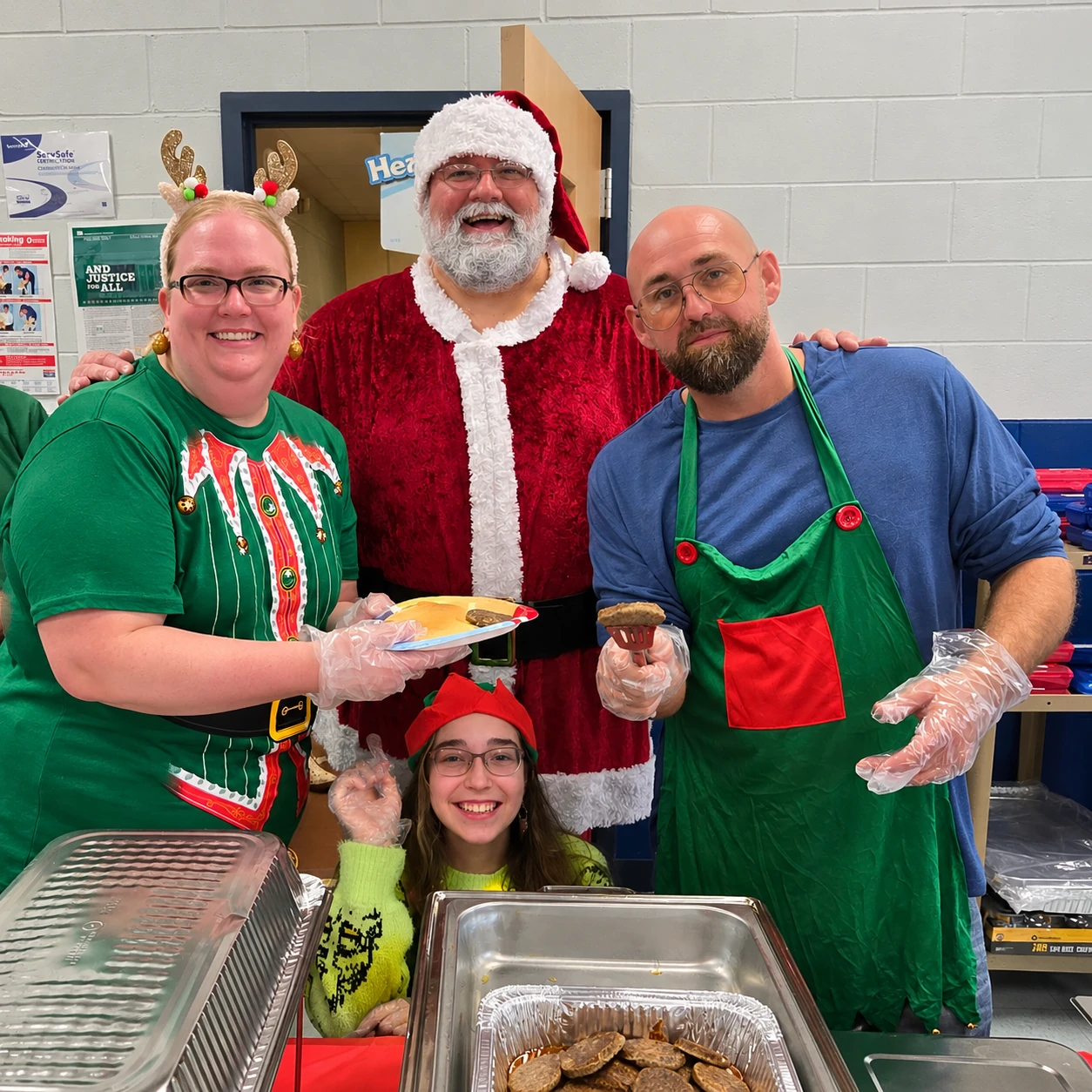 Santa Jeff smiling with a festive breakfast serving crew behind trays of food
